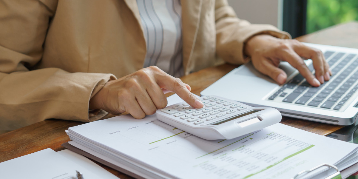 Professional calculating on a laptop with financial documents.
