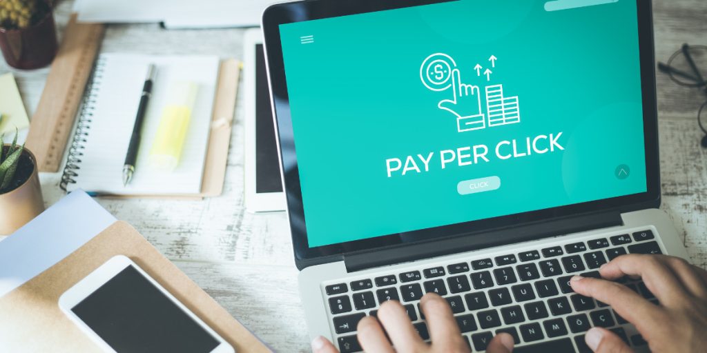 Laptop screen displaying a Pay Per Click marketing graphic on a desk.