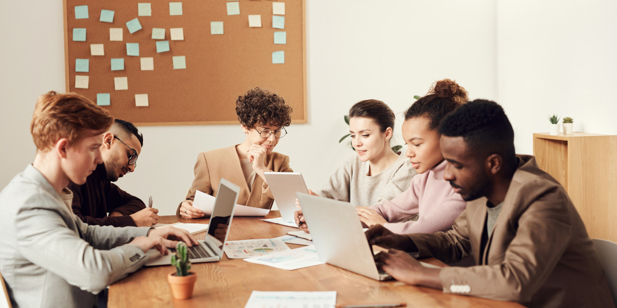 Diverse team of professionals working together on laptops in an office.
